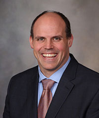 David Linden, PhD, of the Mayo Clinic in Minnesota, will speak at the Sept. 22, 2016, Neuroscience Seminar Series event. He is pictured wearing a black suit jacket, light blue dress shirt and red tie against a gray photo background.