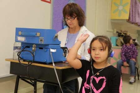Nurse and young girl conducting a hearing test