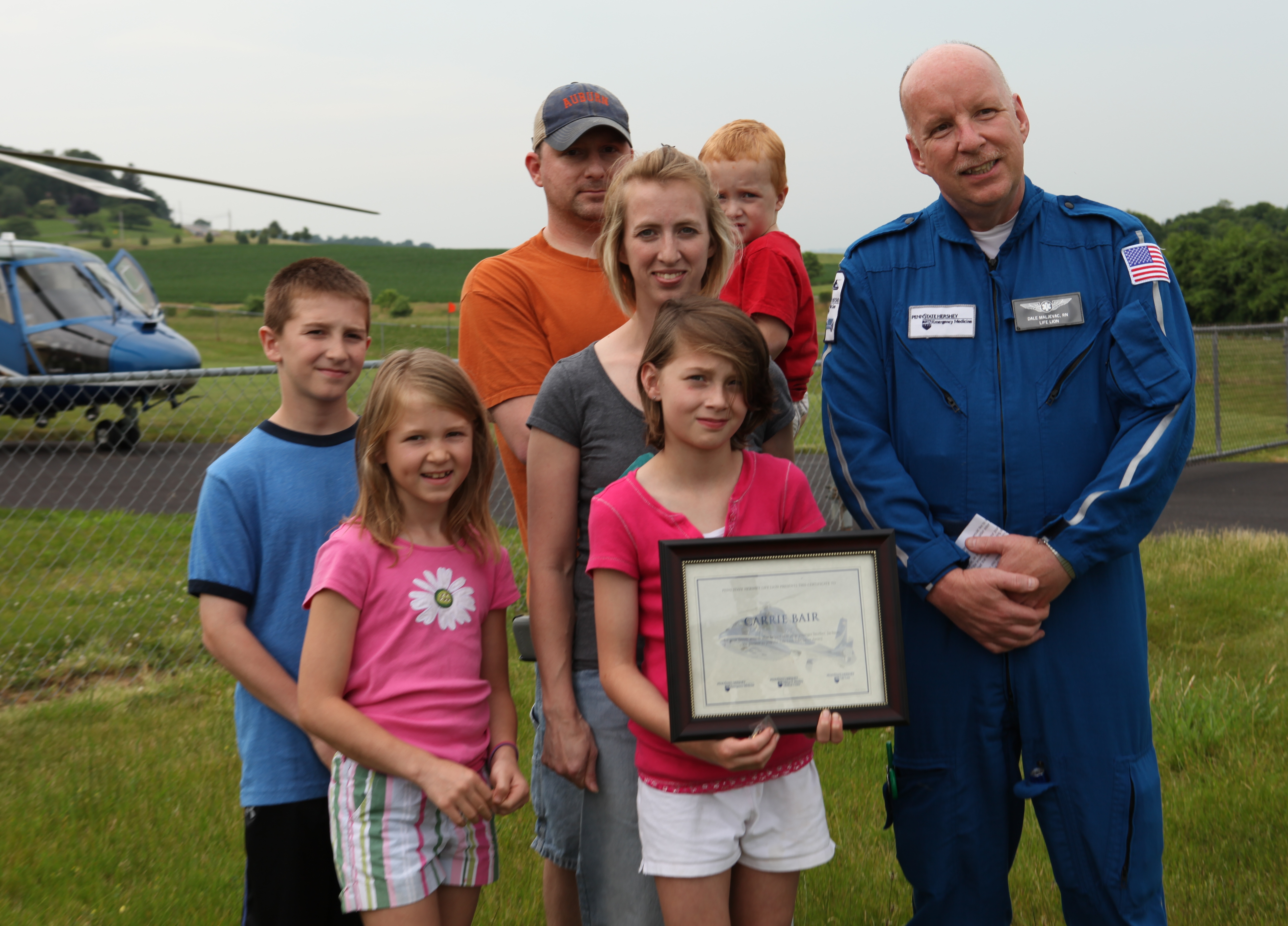 Carrie Bair (front, center) receives a Life Lion Life Saver Award from Dale Maljevac, flight nurse with Penn State Hershey Life Lion Critical Care Transport. Standing behind Carrie are her mom, Amy, and dad, Jason. Jason is holding Carries brother, Jackson. At left are their siblings, Jared and Caeley.