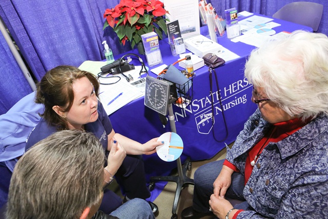 Penn State Hershey nurse Steph Reed talks with a couple about healthy Body Mass Index (BMI) at the 2014 Pennsylvania Farm Show.