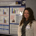 A woman stands in front of an academic poster.