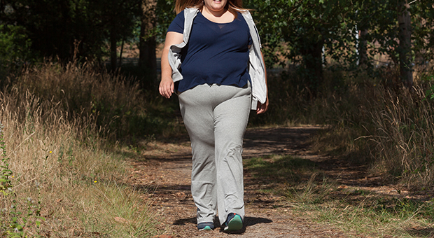 An overweight woman is pictured walking outdoors.