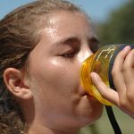 Young soccer player having a drink and pouring sweat.