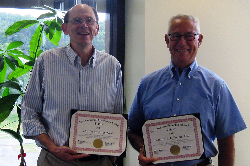 Two faculty from the Department of Cellular & Molecular Physiology were named American Physiological Society Fellows in 2015. Dr. Charles Lang is seen at left, and Dr. Leonard Jefferson is at right. The two men are holding certificates noting their honor and are standing in front of a window.