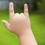 A child's hand gives a sign language motion.