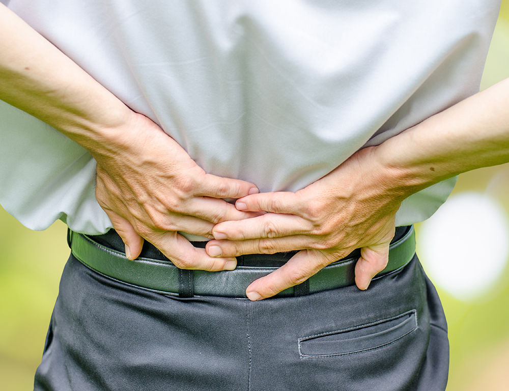 Close up of a man holding his back in pain, isolated on white background.