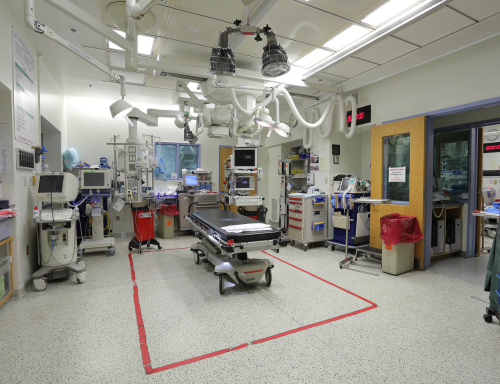 A trauma bay at Hershey Medical Center. A treatment bed is seen in the center of the room. Equipment is located around the perimeter and mounted to the ceiling.