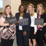 Attendees at the 2016 PA Community and Public Health Conference display signs showing what public health means to them. The six female attendees are shown standing in a conference room, with three of them holding chalkboard signs.