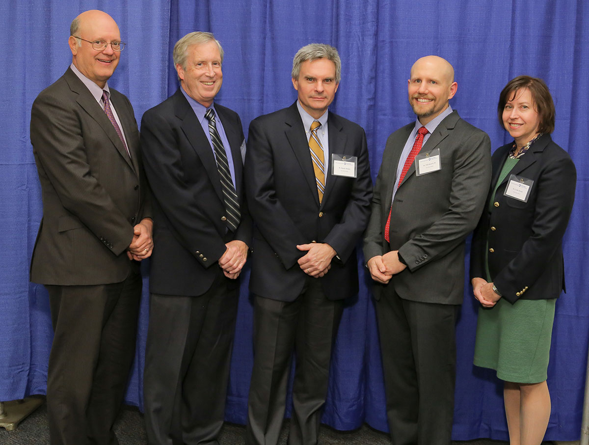 Penn State College of Medicine's 2016 Innovator of the Year award recipient is Will Hazard, MD, second from right. Hazard is pictured with, from left, A. Craig Hillemeier, MD, dean of the College and CEO of Penn State Health; Barry Fell, owner of TPC Design; Randy Haluck, MD, assistant professor of surgery at Penn State College of Medicine; and Leslie Parent, MD, vice dean for research and graduate studies for the College. The five are pictured standing in front of a blue photo backdrop.