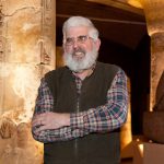 Patrick McGovern, PhD, will speak on the use of alcoholic beverages as medicine in the era before synthetics during a talk Nov. 11, 2016, at Penn State College of Medicine. McGovern is scientific director of the Biomolecular Archaeology Project for Cuisine, Fermented Beverages, and Health at the University of Pennsylvania Museum in Philadelphia, where he is also an adjunct professor of anthropology. He is pictured wearing a plaid collared shirt and brown vest, standing in front of a room with replica ancient artifacts such as a model Sphinx.