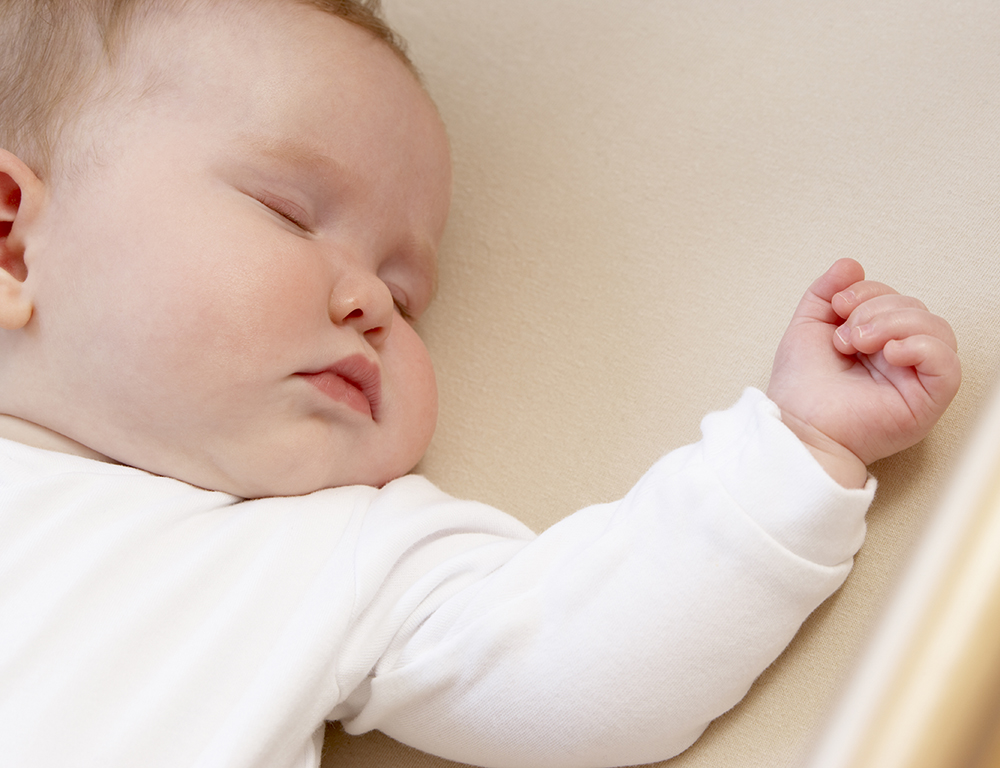 A newborn baby sleeps on his back.