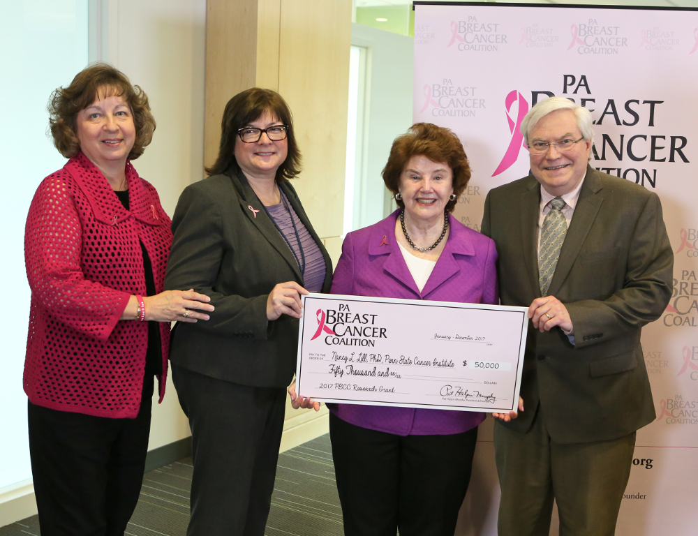 Four people pose with a check in the amount of $50,000. A backdrop with the PA Breast Cancer Coalition logo is behind them.