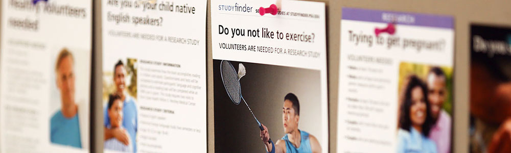Posters advertising a variety of clinical research trials at Penn State College of Medicine are seen on a College bulletin board in summer 2016. The image shows five posters in a line, with the center one in focus and the others out-of-focus in the background.