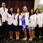 The MD/PhD program at Penn State College of Medicine welcomed eight new students during the 2017 MD Program White Coat Ceremony, held July 28. Pictured from left are new MD/PhD Medical Scientist Training Program students Trisha Basu, Vladimir Khristov, Maryknoll Palisoc, Hannah Bennett, Kristen Manto, Natella Maglakelidze, Nadia DiNunno and Morris Aguilar. The eight students are pictured standing in a large hall, in a single-file line against a wall. All are wearing short white coats denoting their status as medical students.