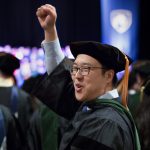 Penn State College of Medicine's Commencement was held at Founder's Hall at the Milton Hershey School on May 21, 2017. Pictured, Adrian Wang, MD, cheers during the ceremony. Wang is pictured wearing a cap and gown with his right hand extended in the air.