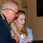 Mary Elizabeth McCulloch of VozBox demonstrates to Ed Arnold her team's accessible technology app for individuals with communication disabilities during the Oct. 17, 2017, Innovation CafÃ© at the Cocoa Beanery. The two are pictured standing side-by-side and looking at a laptop computer.
