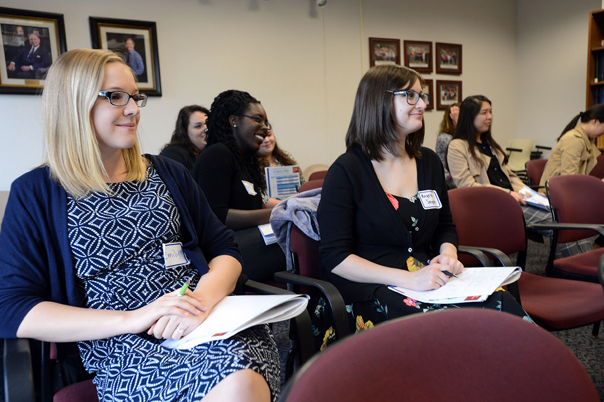 Graduate students listen to the Outreach/Secondary Education panel at the 2017 Career Day event. Picture are, from left, Emily Blanke, PhD candidate, Neuroscience; Jaclyn Welles, PhD candidate, Biomedical Sciences; and Angela Snyder, PhD candidate, Neuroscience. The women are pictured sitting in chairs in a large conference room, smiling and looking at a presenter who is not seen in the picture.