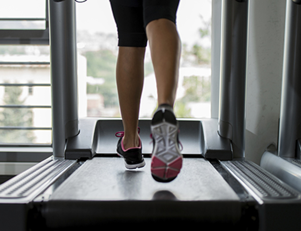 A runner™s legs on a treadmill. The runner is wearing sneakers.
