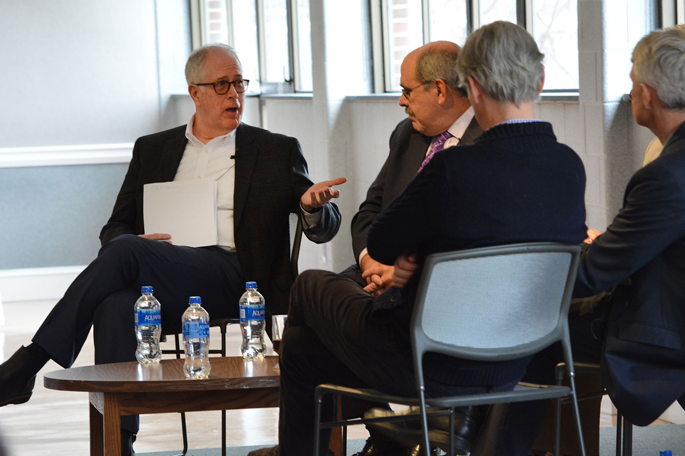Kevin Harter, professor of practice of entrepreneurship and the director of the Center for Medical Innovation at Penn State College of Medicine, left, takes part in a discussion following Steven Johnson's talk at Penn State Harrisburg in March. Harter is pictured at left in a group of four seated people in business attire. The four are engaged in conversation in a large meeting space.