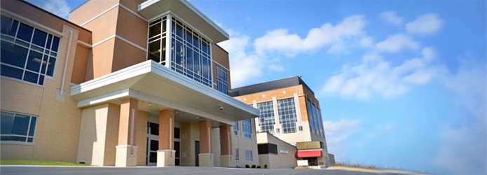 The Lance and Ellen Shaner Cancer Pavilion is pictured in State College, PA. The building is visible in a wide horizontal photo with a blue, lightly cloudy sky visible to the right.