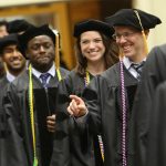 Ben Abney acknowledges someone in the audience as he joins his fellow graduates while entering the 48th commencement for Penn State College of Medicine, held May 20, 2018, at the Hershey Lodge. Abney is pictured smiling and pointing, and a row of other students is visible behind him.