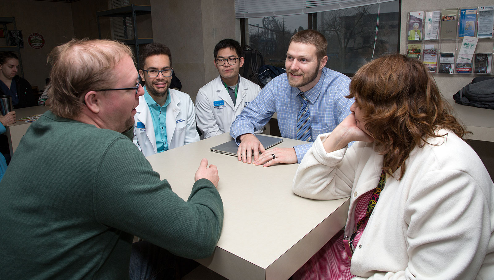 Penn State College of Medicine students work with people at Hershey Plaza Apartments as part of a health fair event. The students are pictured sitting around a square table.