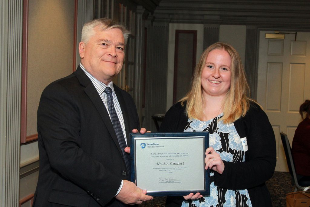 Kristin Lambert, a doctoral candidate in Biomedical Sciences and a student in the MD/PhD Medical Scientist Training Program, received the Penn State Alumni Association Scholarship in April 2018. She is pictured with University President Eric Barron. The two are standing side by side, each holding one side of a certificate with Lambert's name.