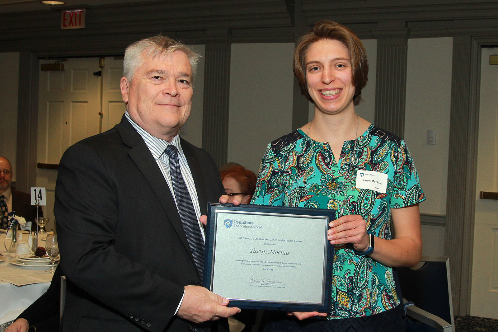 Taryn Mockus, a doctoral candidate in Neuroscience, received the University's Graduate Student Excellence in Mentoring Award in April 2018. She is pictured with University President Eric Barron. The two are standing side by side, each holding one side of a certificate with Mockus' name.