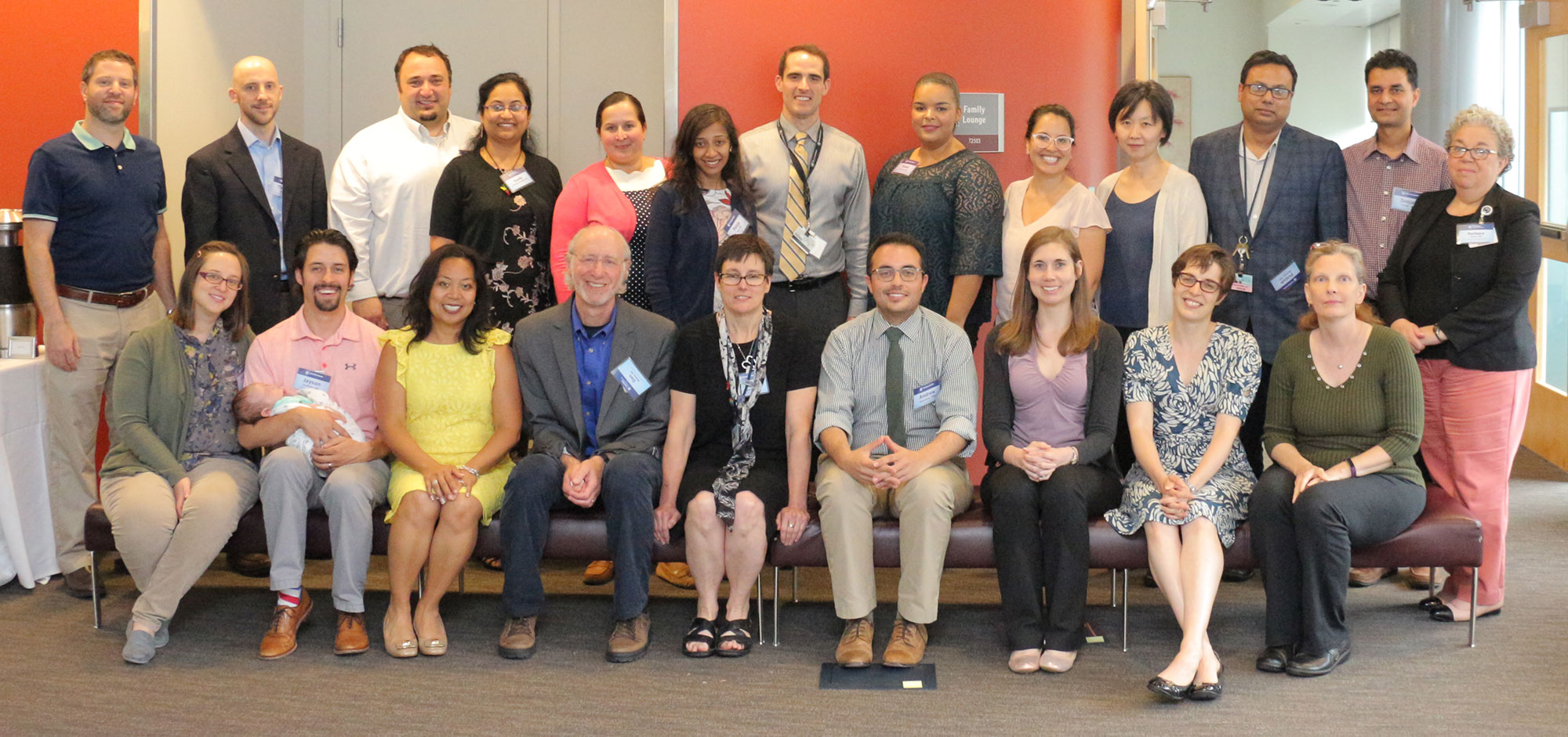 The 2017-2018 participants in Penn State College of Medicine's Junior Faculty Development Program are pictured with program leadership in May 2018. The faculty are pictured sitting and standing in two rows in a large meeting space.