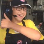 A young boy wearing a Dairy Queen uniform looks at the camera and smiles, giving a thumbs-up with his left hand.