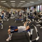 Penn State College of Medicine's University Fitness Center is seen in a 2013 panoramic photo. Various equipment and weight benches can be seen in rows, with mirrors along one wall. People are using some of the equipment.