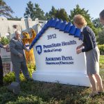 Four people stand around an outdoor sign that reads: Penn State Health Medical Group Andrews Patel Hematology/Oncology
