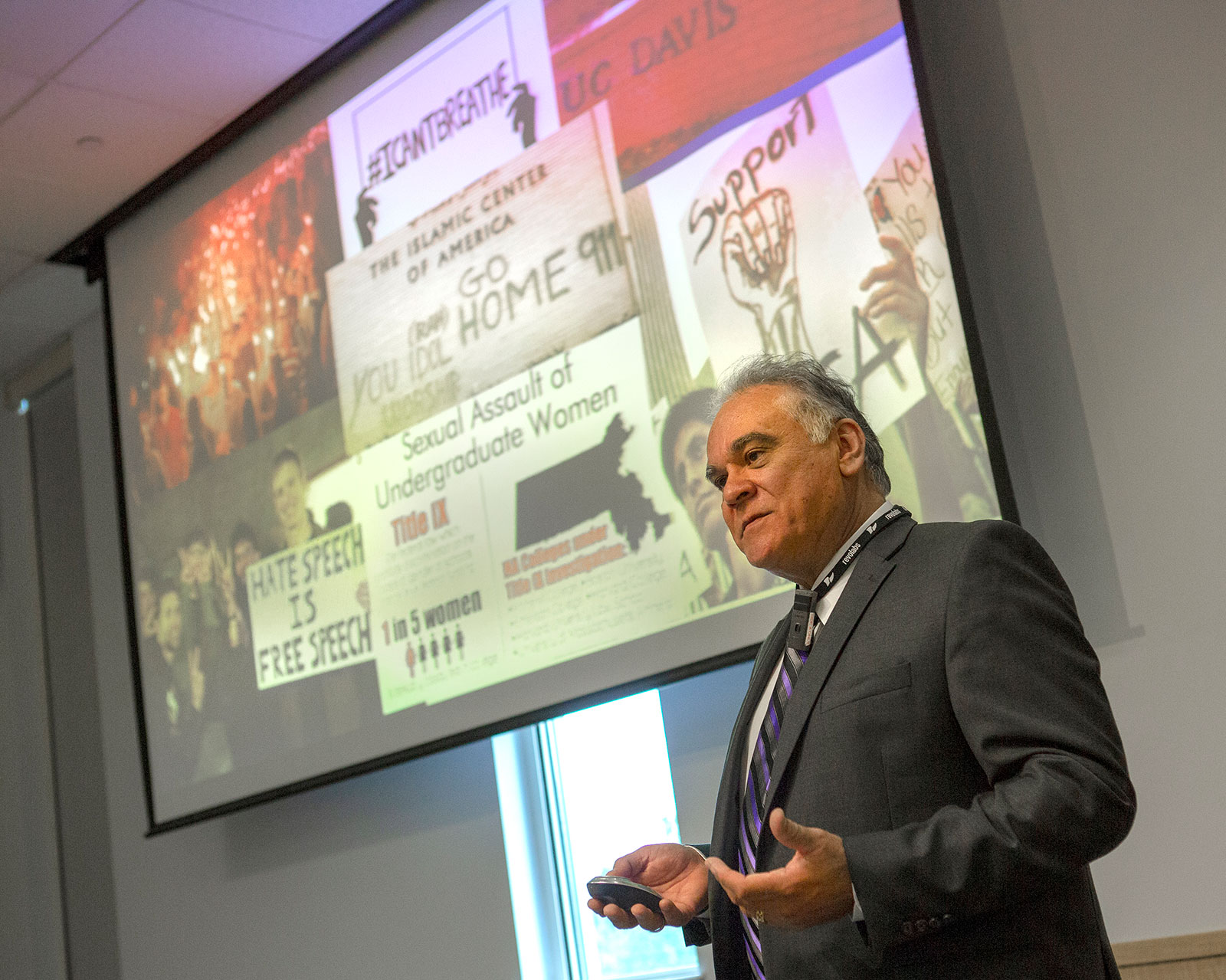 David Acosta, chief diversity officer with the AAMC, is pictured speaking at an event in August 2018 at Penn State College of Medicine in Hershey, PA. Acosta is seen in the foreground with a large presentation screen behind him depicting images related to bias.