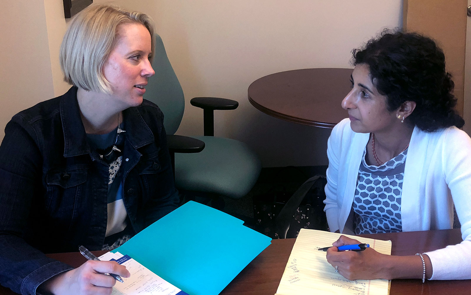Dr. Jennifer Kraschnewski and Dr. Deepa Sekhar are pictured sitting at a table with folders open in front of them.