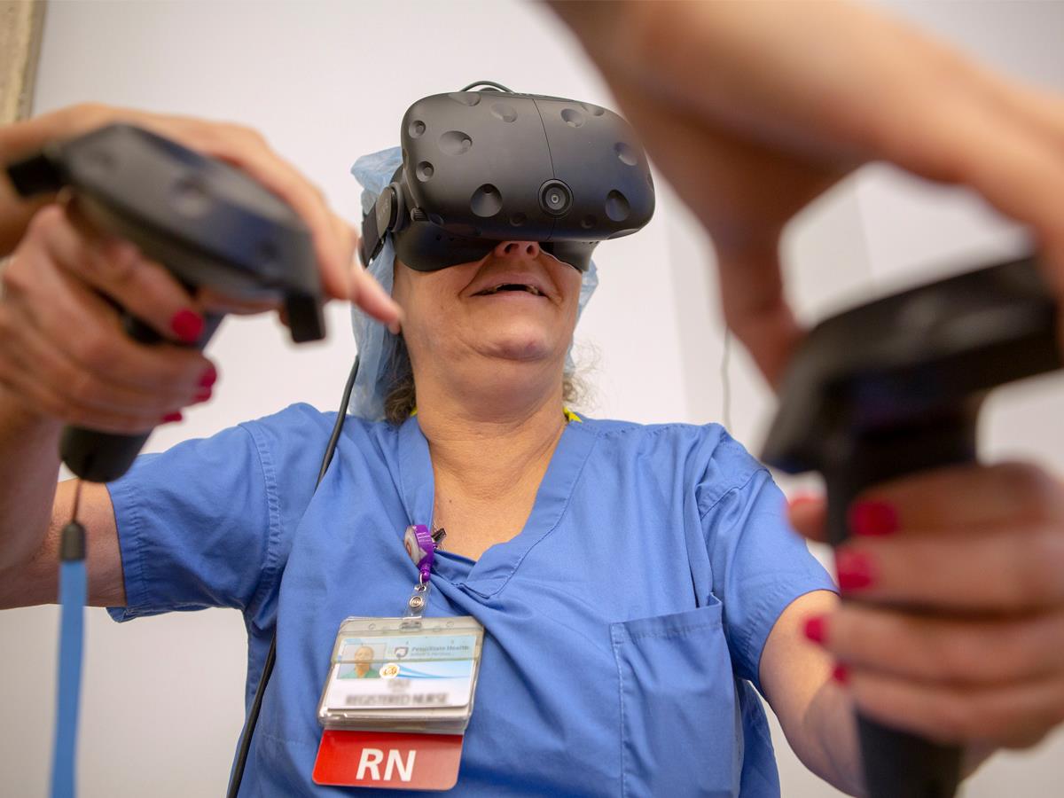 Dale Acela, a registered nurse at Penn State Health Milton S. Hershey Medical Center, tries her hand at VR during her visit to the Day of Making event at Harrell Health Sciences Library in August 2018. She is pictured wearing scrubs and a VR headset.
