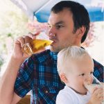 On the left is a photo of a man drinking a beer while a young child sits in his lap, drinking milk. On the right is text reading: "Ask Us Anything About...Alcohol Use Disorder"