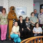 A group of people, including a college mascot dressed as a lion, smile for a photo.