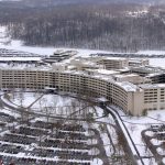 An aerial view of the Penn State Health Milton S. Hershey Medical Center campus shows the Crescent, parking lots and a hill behind the medical center covered in snow.