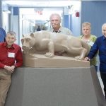 Penn State College of Medicine’s Mini Medical School participants, from left, "Sir" Robert Griscavage, Bonifacio Dewasse, Robert Hairston, Ruth Miller, William Miller, Rebekah Miller, Perry Emes, Marylou Martz and Joan Decker pose in front of a Nittany Lion statue in the rotunda of Hershey Medical Center. Behind them a hallway is visible.
