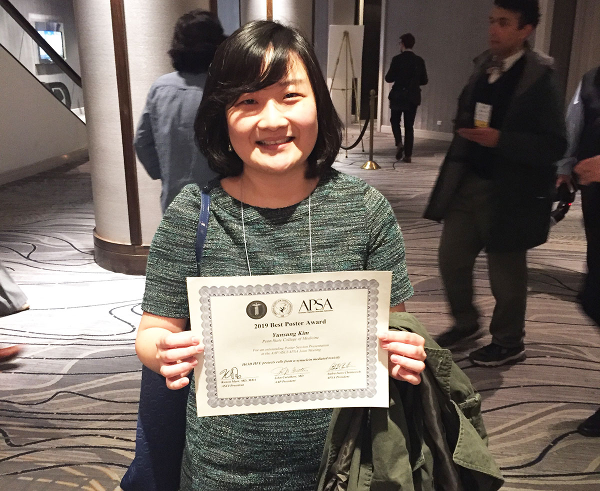 A woman is seen in a conference lobby holding a certificate.