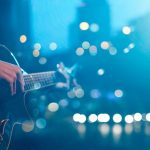Hand of guitarist playing on stage. Backgound is out of focus.
