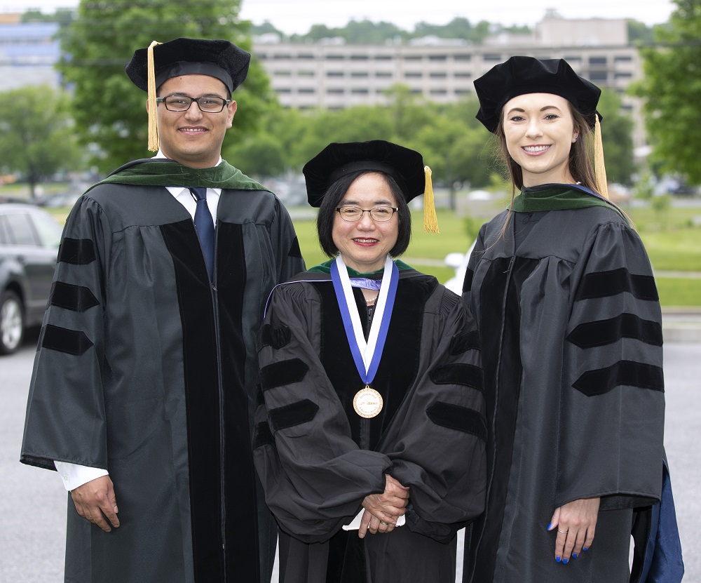 Dr. Peter Zaki, Dr. Shou Ling Leong and Dr. Sarah Stovar stand in a row in commencement caps and gowns.