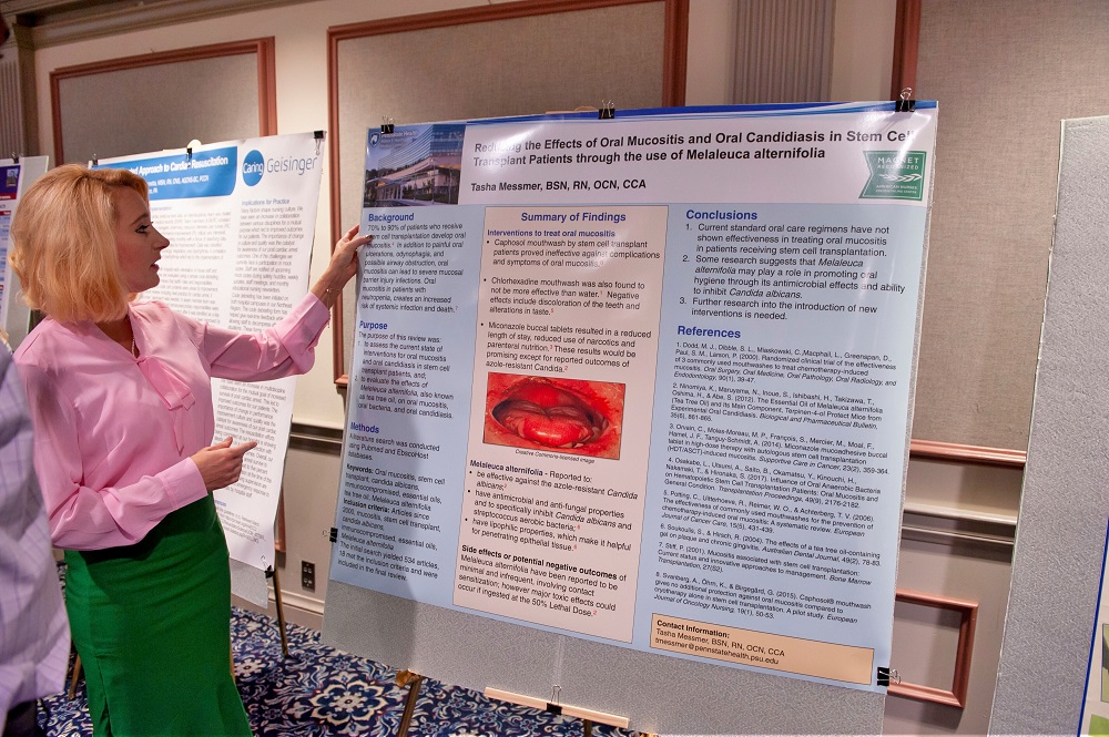 A woman’s hand rests upon the edge of a poster resting on an easel.