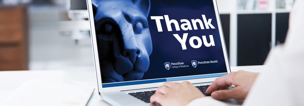 Hands can be seen typing at a laptop keyboard. On the screen is an image of the Penn State Nittany Lion statue and the words Thank You.