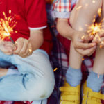 Two children hold sparklers in their hands.