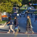 Three women walk in a crosswalk from Centerview Parking Garage to University Physician Center on the Hershey Medical Center campus. Behind them is another crosswalk, a traffic light and signs.