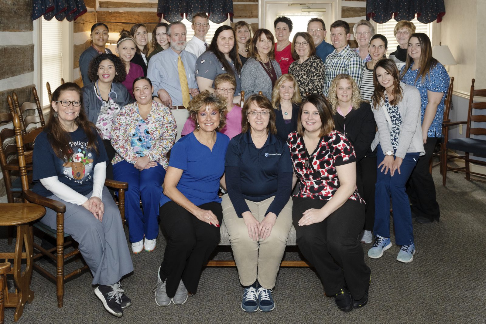 A room full of people pose for a photo. Some sit in chairs. Others stand.