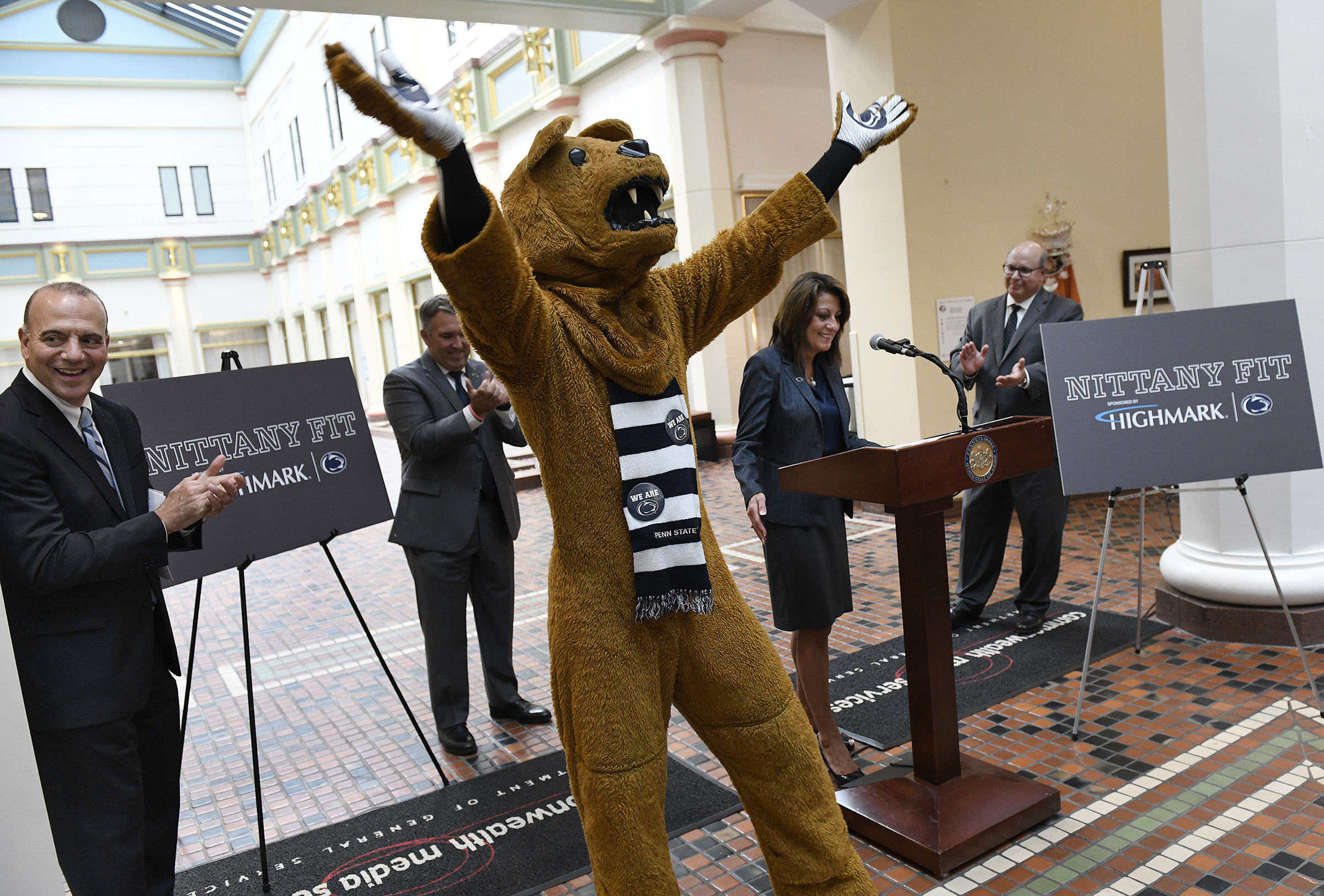 A man in a mascot costume cheers as a crowd watches