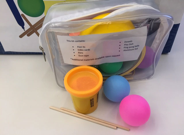 A small plastic bag is seen containing Play-Doh, craft sticks, tape, small balls and more.