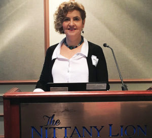 A woman stands at a podium with a microphone in front of her.